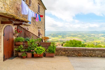 Foto op Canvas A medieval stone building with laundry hanging overlooking the hills and countryside of Tuscany in the hill town of Volterra, Italy. © Kirk Fisher