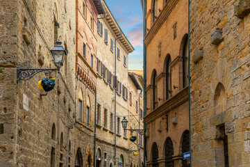 Fototapeta na wymiar Medieval homes and apartments above shops in one of the historic streets of Volterra, Italy, in the Tuscany region.