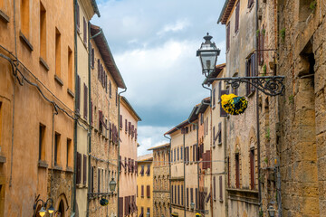 Medieval homes and apartments above shops in one of the historic streets of Volterra, Italy, in the Tuscany region.