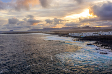 Obraz premium aerial view on white village on coast with ocean waves on lanzarote