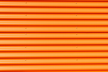 Wall made of strips of aluminum profile orange color. Horizontal lines.