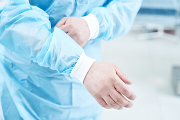 Close up of unrecognized doctor putting on uniform
