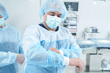 Senior surgeon putting on uniform for operation