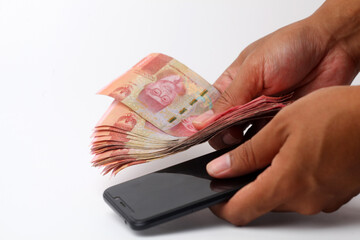 Hand holding cellular phone and banknotes. Isolated on white background with copyspace