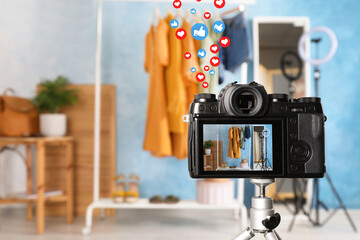 Rack with stylish clothes and mirror near light blue wall indoors, focus on camera screen
