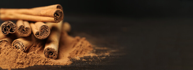 Aromatic cinnamon sticks and powder on table, closeup view with space for text. Banner design - Powered by Adobe