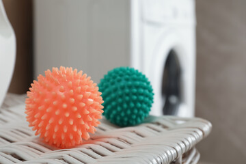 Dryer balls on wicker basket near washing machine in laundry room, closeup