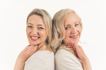 Caucasian beautiful middle-aged calm women standing back to back, touching their faces, looking at the camera. Studio shot. High quality photo