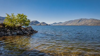 Fototapeta na wymiar Okanagan Lake, Canada. Summer landscape of a lake and mountains in the background in early morning
