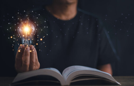 Thinking and creative concept, Hand holding light bulb on the open book, Knowledge and searching for new ideas, Education, Innovations, self-learning, Inspiring from read.