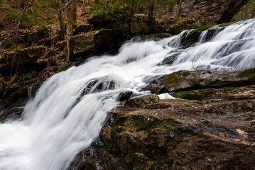 A stream cascades down over rocks into a pool of water.