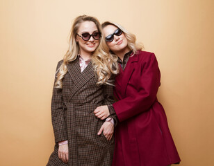 Fashion and beauty concept: Two young women posing in nice clothes, coat, sunglasses.