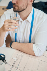 Male tailor drinking water during sewing in workshop