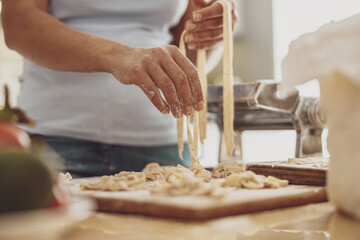 Wooden kitchen board with homemade noodles lined with noodle cutter