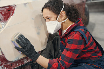 Serious woman polishing primer before auto coloring