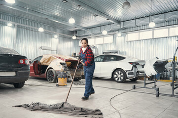 Attentive female person cleaning territory of workshop