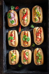 Unhealthy and tasty mini hot dogs with mustard and herbs.