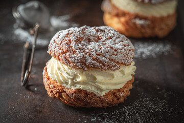 Tasty and homemade cream puffs with powdered sugar in strainer.