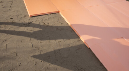 The polyplex polystyrene slab is laid on wet sand as insulation for the foundation of an outdoor swimming pool
