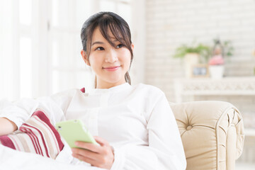 部屋でスマホを見る女性