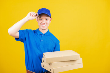 Fototapeta na wymiar Portrait excited delivery service man standing he smile wearing blue t-shirt and cap uniform hold give food order pizza cardboard boxes looking to camera, studio shot isolated on yellow background