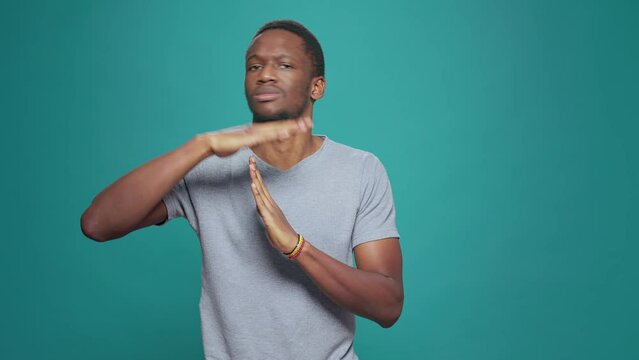 Serious tired person advertising timeout symbol with hands, doing t shape sign to express half time and break. Exhausted man refusing to work, declining and ingoring control. Stop gesture.
