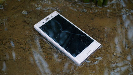 Smartphone with a stretched position in the water and muddy ground. Waterproof smartphone.