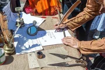 An outdoor master class for teaching ancient Oriental writing. A man writes ancient letters with a quill pen