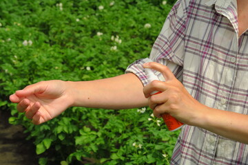 a female farmer applies mosquito and tick spray to her skin to protect herself from infections while working on a farm