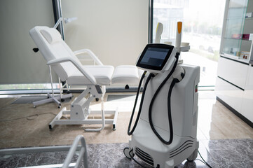 Empty beautician office with white couch and photorejuvenation machine. 