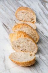 Fresh sliced baguette bread on marble table. Healthy eating breakfast.