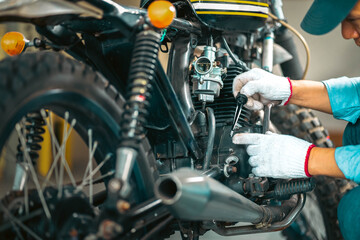 Choseup man mechanic in garage or workshop inspecting classic motorcycle during the maintenance and...