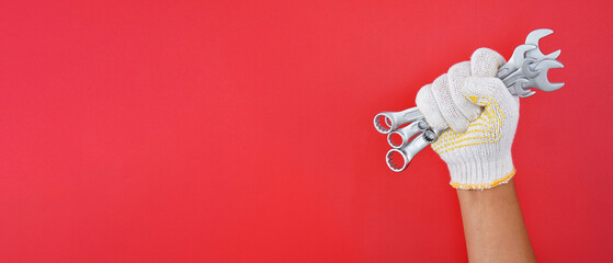 hand wearing white gloves holding combination wrench isolated red background