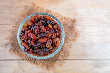 Top view of raisin in glass bowl on wooden background with space for your text.