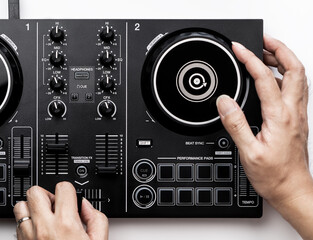 DJ hands is mixing music on DJ Digital mixing controller top view on white background.