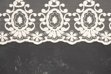 White lace on black concrete background horizontally with copy space. Contrast of tender and rough