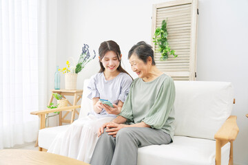 リビングでスマホを使う孫と祖母