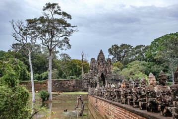 Bridge over the river into Angkor Thom with sandstone carvings of angels and giants adorning both sides in Siem Reap, Cambodia 