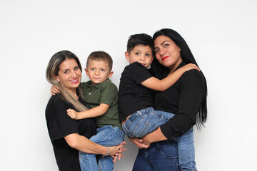 Two moms and two male sons young children pose for family portrait very happy show their love and...