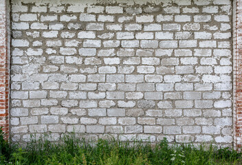 Texture from old brickwork. Agricultural building wall. Green grass grows below.