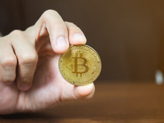 Close up man hand showing golden bitcoin on the table