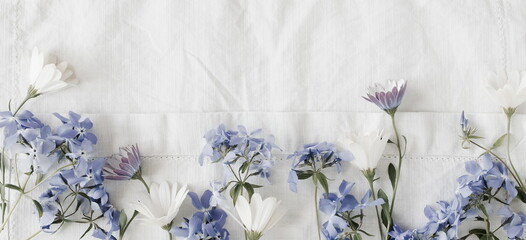 Flowers background. White and blue summer flowers pattern frame on white  linen texture background top view banner. Copy space.Poster