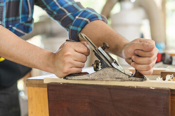 Carpentry professional, asian young man, male carpenter use machines or tool, shavings rugged on wood, timber at industrial. Woodwork, furniture making, construction industry. Owner small business.