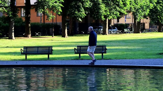 Stockholm, Sweden A man walks around the fountain in Tessinparken in Ostermalm. 