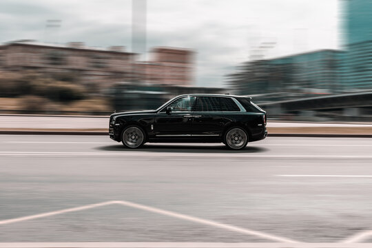 Fast moving car Rolls-Royce Cullinan on the city road. Premium black SUV auto in fast motion with blurred background.