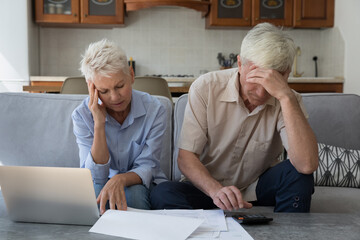 Older stressed unhappy wife and husband manage family finances feeling desperate due debts, unpaid...