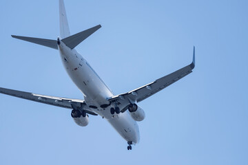 青空を背景に羽田空港に着陸態勢に入る飛行機