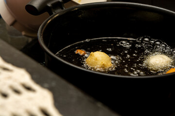 picking up fried dough known as a 'bolinho de chuva' with a slotted spoon. typical and traditional brazilian snack.