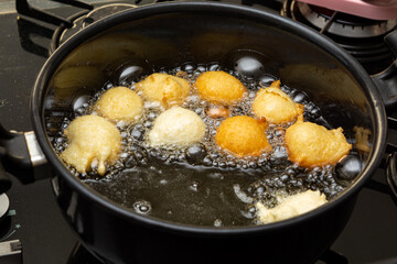 picking up fried dough known as a 'bolinho de chuva' with a slotted spoon. typical and traditional brazilian snack.