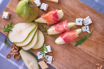 Jamon or prosciutto ham slices, Blue cheese, pears and walnuts on wooden board